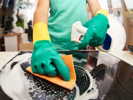 Local technician cleaning a cooker in a North London kitchen